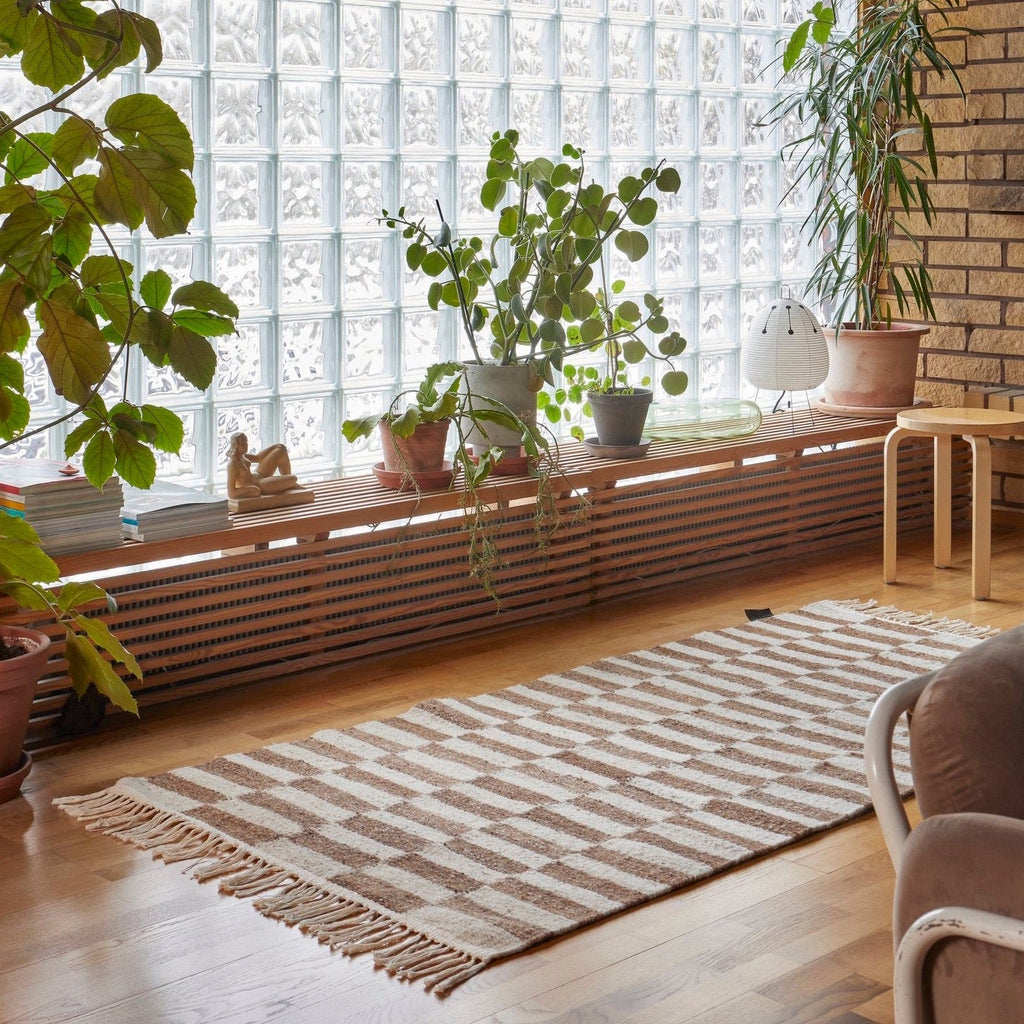 A living room with a large window featuring the Abeba Rug by Sera Helsinki.