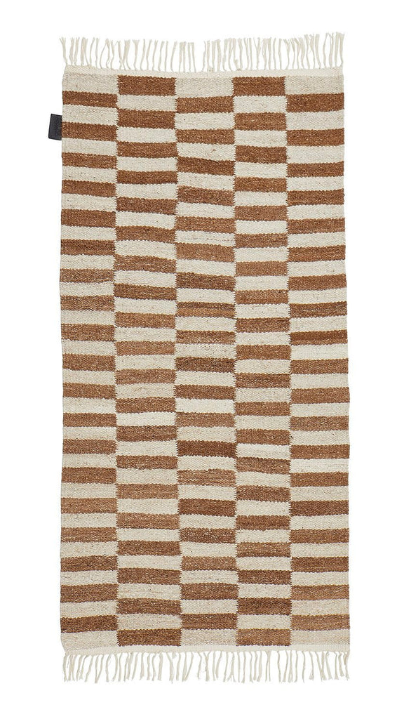A brown and white THE ABEBA RUG with fringes from SERA HELSINKI, available at Gestalt Haus.