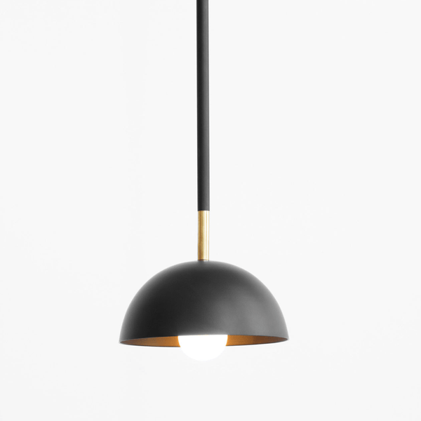 A Lambert et Fils black and gold pendant light called "The Beaubien Simple Shade" hanging on a white wall in the Gestalt Haus.