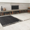 A black and white E-1027 RUG by SERA HELSINKI in front of a Gestalt Haus fireplace.