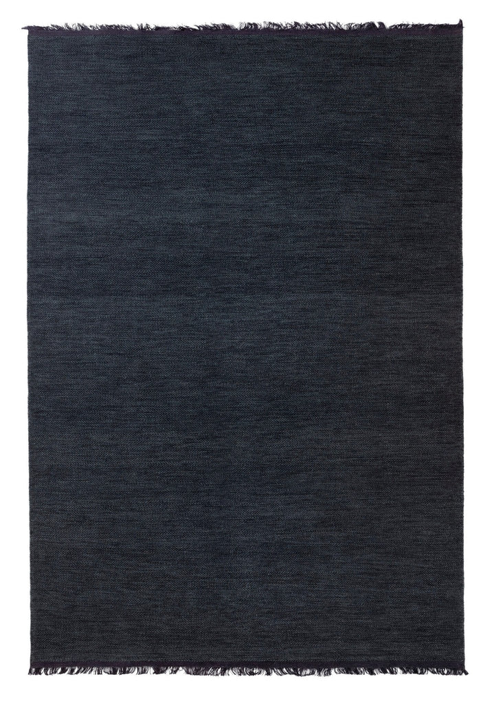 A dark blue Felicia rug with fringes on a white background by Fabula Living, inspired by Gestalt Haus design principles.