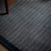 A blue and white Fabula Living rug from the Gestalt Haus collection on a wooden floor.