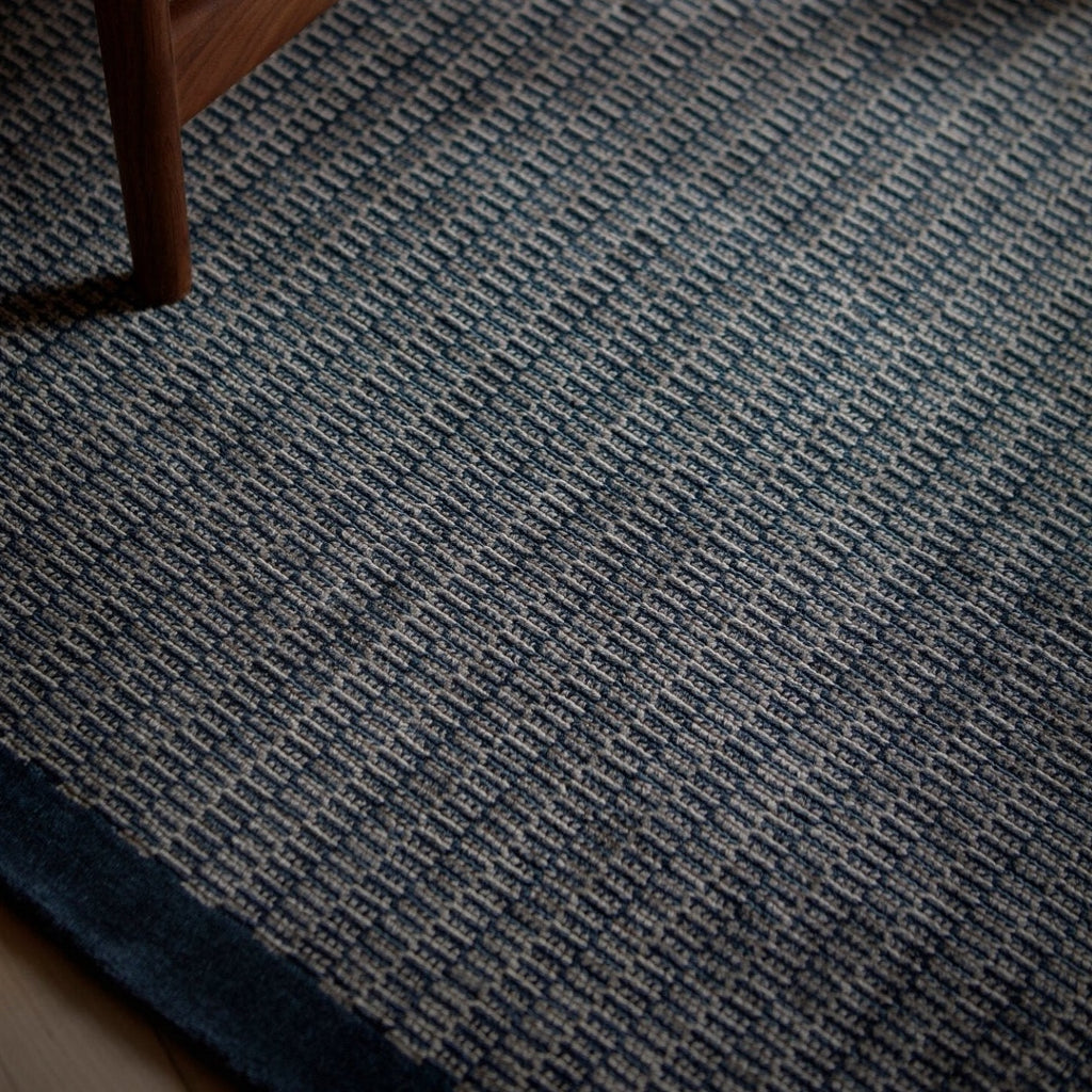 A blue and white Fabula Living rug from the Gestalt Haus collection on a wooden floor.