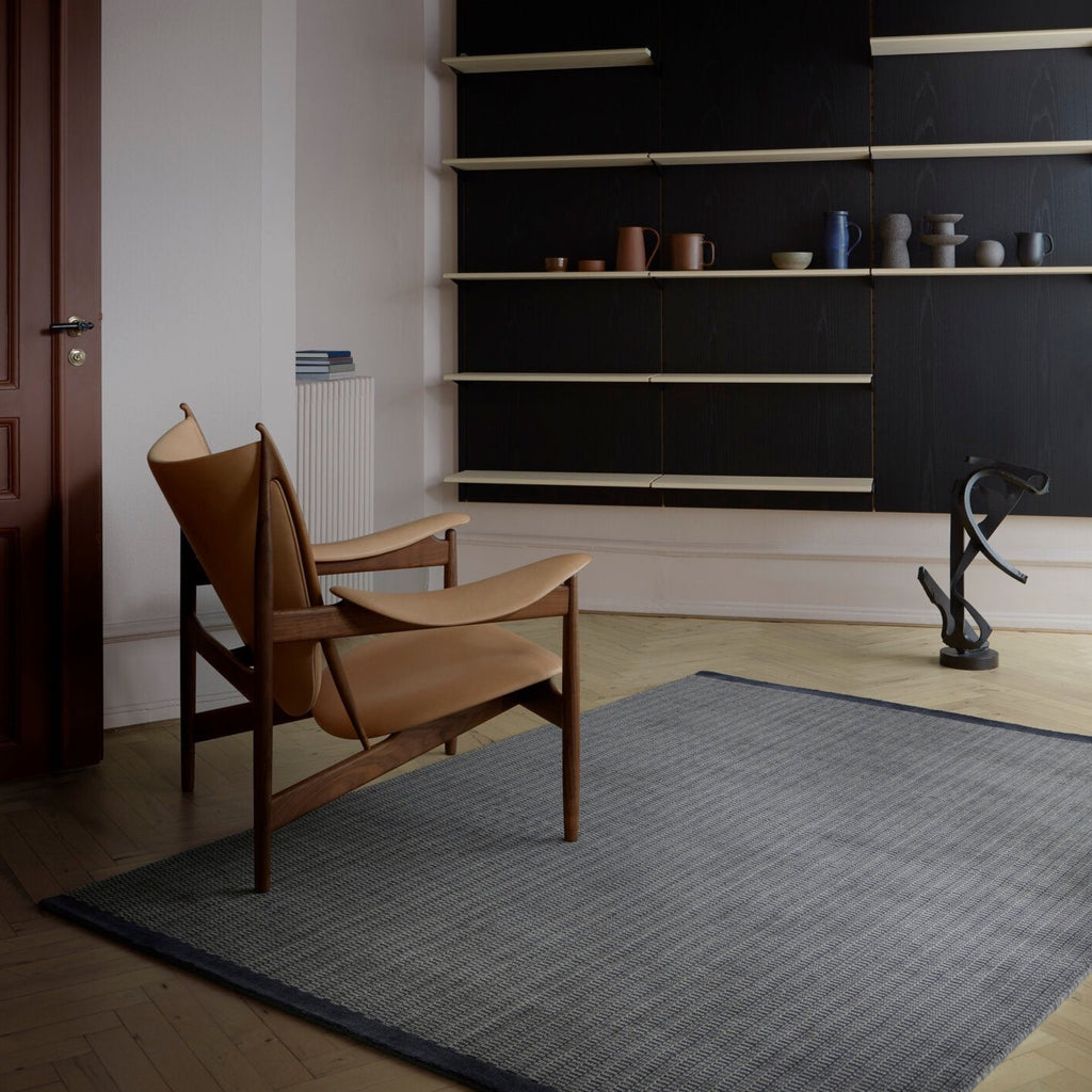 A room with shelves and a chair in front of THE GRO RUG by FABULA LIVING in a Gestalt Haus.