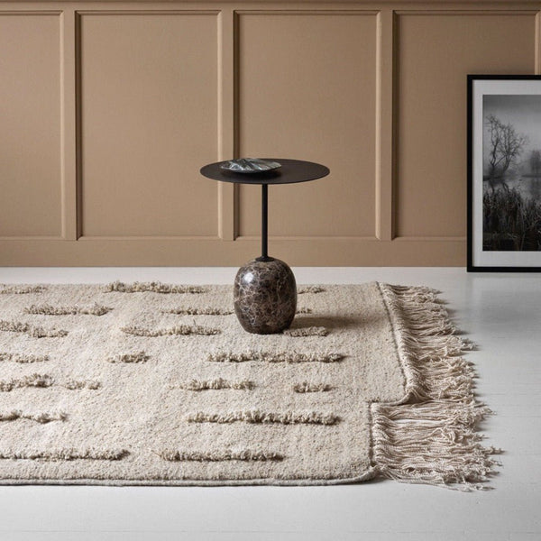 A SERA HELSINKI rug with fringes, THE LAINE RUG, in a room with beige walls at Gestalt Haus.