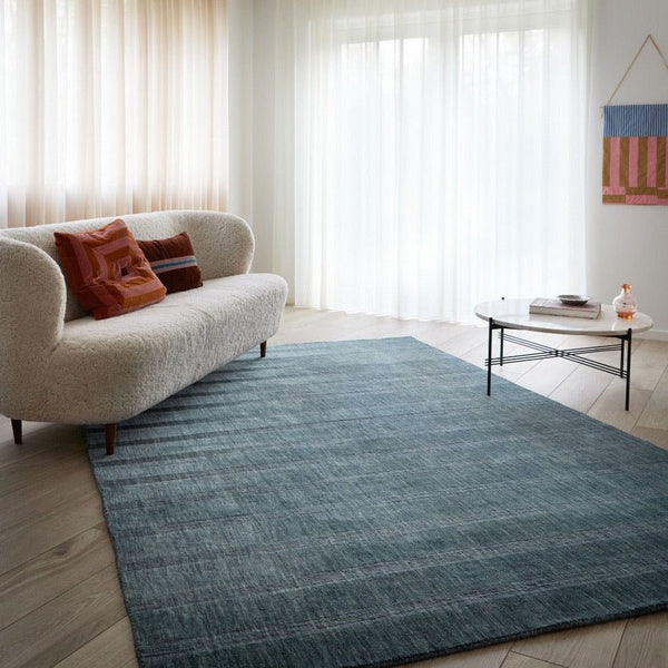 A THE LILY RUG by FABULA LIVING enhances the living room ambiance with a touch of Gestalt.