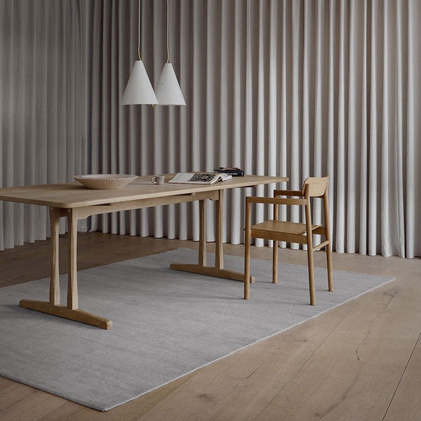 A Fabula Living wooden dining table in a Gestalt Haus room with curtains.