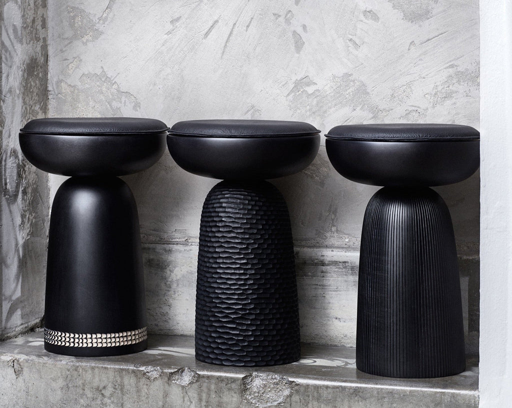 Three black Nera stools by Zanat sitting on top of a concrete wall at Gestalt Haus.