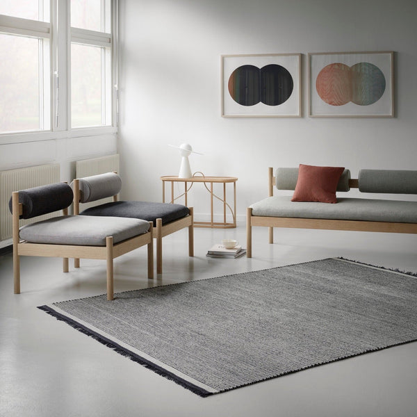 A living room with a couch, chairs and THE NJORD RUG by FABULA LIVING inspired by Gestalt Haus.