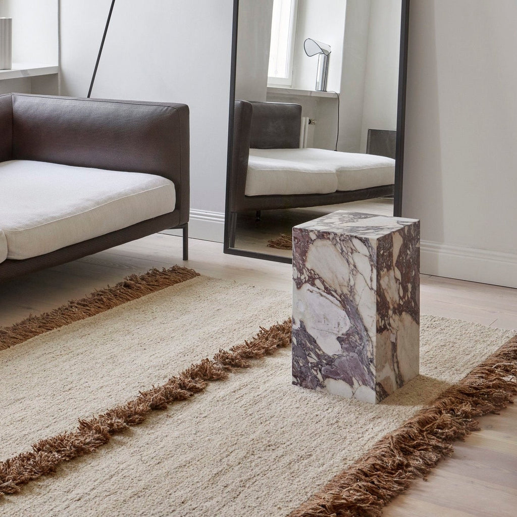 A living room with a brown Serä Helsinki Nurja Rug and a mirror designed in the style of Gestalt Haus.