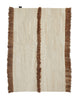 A beige and brown NURJA RUG by SERA HELSINKI with fringes offered at Gestalt Haus.