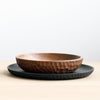 A wooden touch bowl and a black plate on a Gestalt Haus table.
