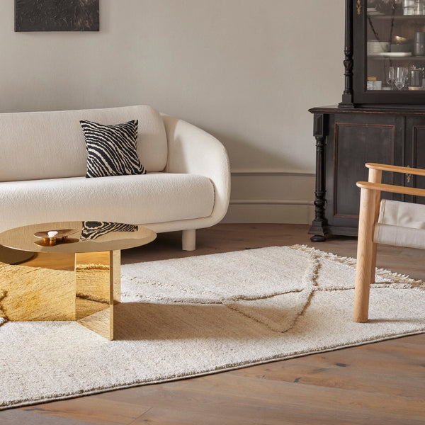 A living room with a white couch, gold coffee table, and the Vuoristo rug from Sera Helsinki in Gestalt Haus style.