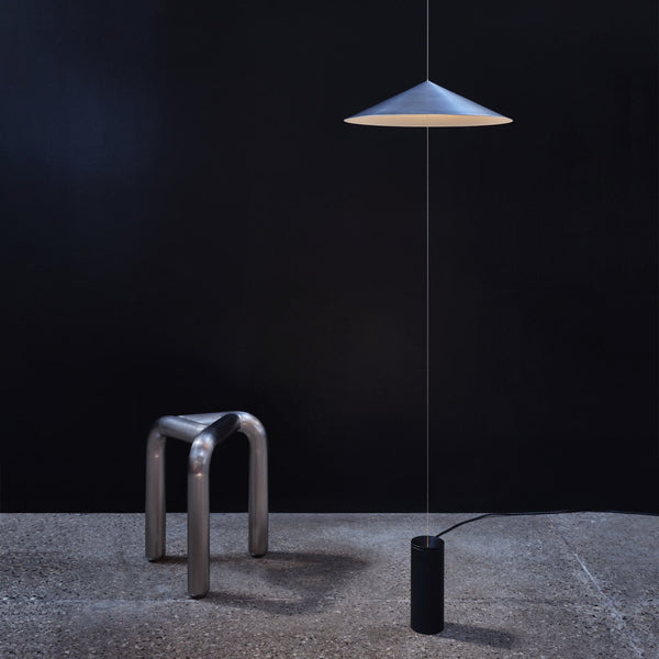 A dark room featuring the ANONY WISP LAMP and a stool, inspired by the minimalist aesthetics of Gestalt Haus.