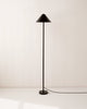 A black IN COMMON WITH Eave Floor Lamp stands gracefully on a white floor.