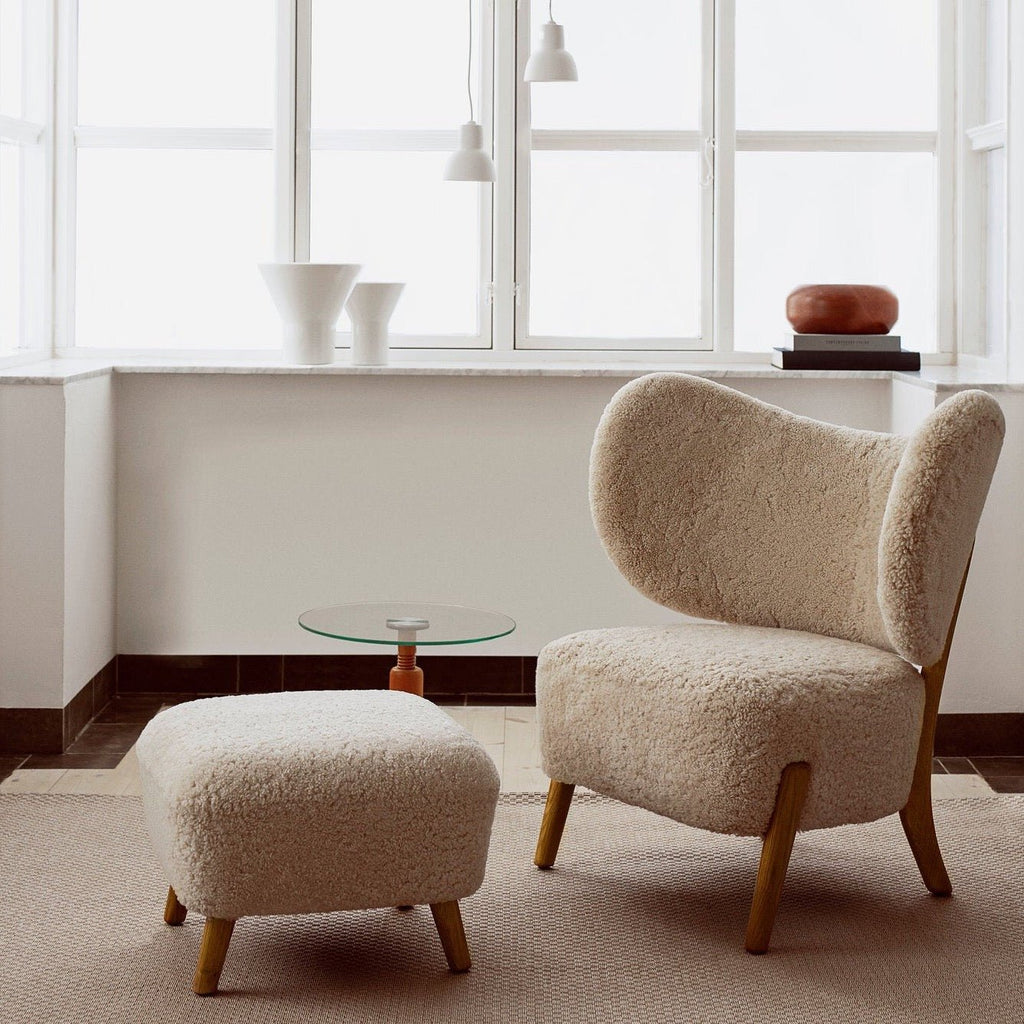 A Gestalt Haus lounge chair and ottoman in front of a window.