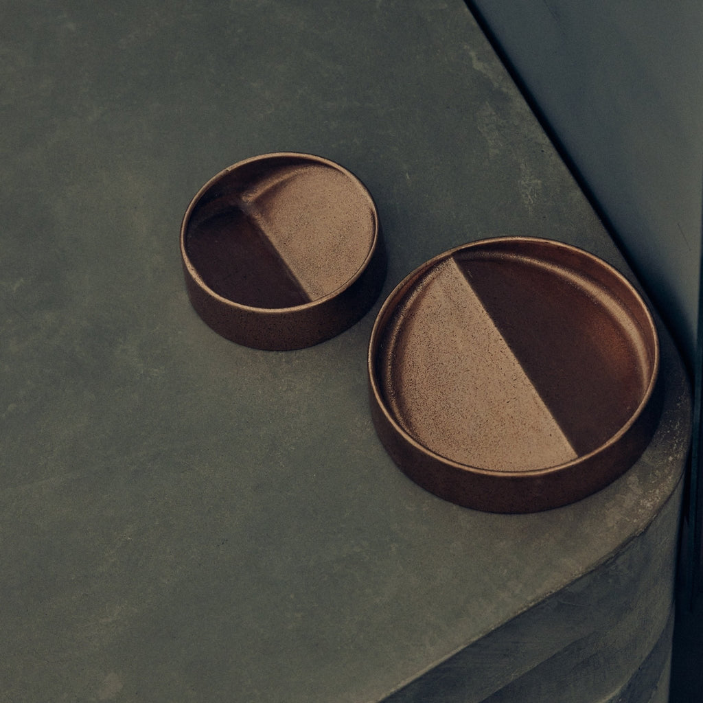A pair of VIDE POCHE ROND bowls by STUDIO HENRY WILSON sitting on top of a concrete surface at Gestalt Haus.